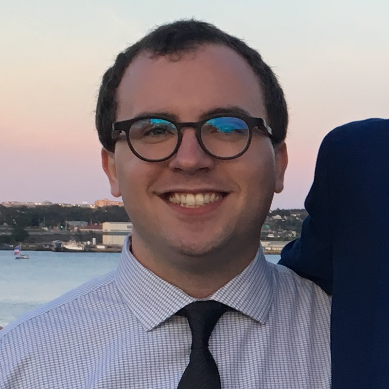 Darien DeWolf smiling in front of the Halifax Harbour.